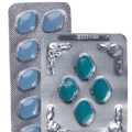 Two silver blister packs containing oval-shaped pills, one filled with light blue pills and the other with teal-green pills, shown on a white background.